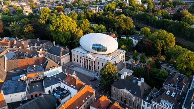 Aerial view of Museum de Fundatie with its iconic white oval roof structure surrounded by historic buildings and lush urban greenery in Zwolle Overijssel Netherlands.
