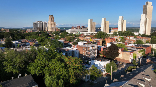 Aerial view of the Albany skyline featuring the Empire State Plaza towers historic buildings and lush green trees under a clear blue sky in Albany New York United States.