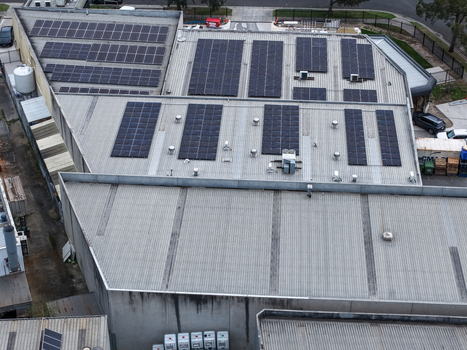 Melbourne VIC Australia 25 September 2026 Aerial view of an industrial facility roof featuring extensive solar panel arrays corrugated metal surfaces and ventilation units.