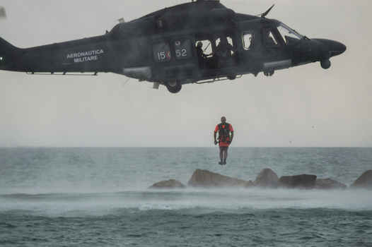 Porto San Giorgio Italy 13 September 2015 View of an Aeronautica Militare Italiana helicopter performing a search and rescue exercise with a rescuer suspended over the sea.