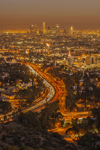View of the Los Angeles skyline at night with illuminated skyscrapers and light trails from traffic on the highway Los Angeles California United States. View of the Los Angeles skyline at night with illuminated skyscrapers and light trails from traffic on the highway Los Angeles California United States.