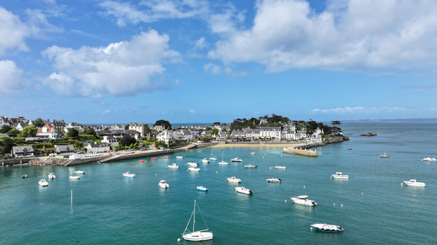 Aerial view of the coastal town of Locquirec featuring a harbor filled with white boats and stone houses along the waterfront Locquirec Brittany France. Aerial view of the coastal town of Locquirec featuring a harbor filled with white boats and stone houses along the waterfront Locquirec Brittany France.