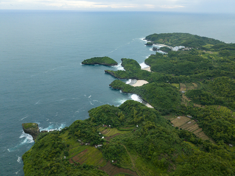 Aerial view of verdant cliffs meeting the turquoise sea at Sedahan Beach where emerald forests contrast with the white sands Gunungkidul Regency Special Region of Yogyakarta Indonesia. Aerial view of verdant cliffs meeting the turquoise sea at Sedahan Beach where emerald forests contrast with the white sands Gunungkidul Regency Special Region of Yogyakarta Indonesia.