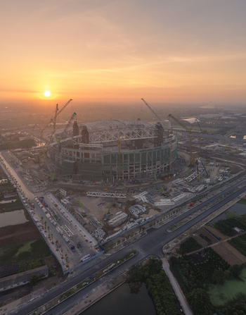Aerial view of the PVF Stadium under construction with large cranes and steel framework illuminated by the warm glow of sunset in Hanoi Ha Noi Vietnam.