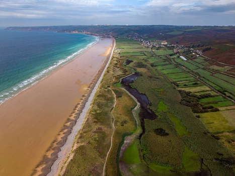 Aerial view of the Dunes de Biville coastline featuring sandy beaches lush green fields and wetlands in La Hague Normandie France.