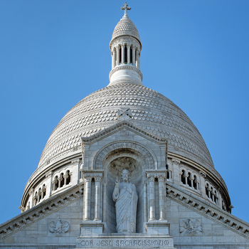 View of the white dome and statue of Jesus at the Basilique du Sacre Coeur de Montmartre under a clear blue sky with intricate stone carvings Paris Ile de France France. View of the white dome and statue of Jesus at the Basilique du Sacre Coeur de Montmartre under a clear blue sky with intricate stone carvings Paris Ile de France France.