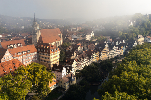 Aerial view of the historic old town with Stiftskirche church traditional half timbered houses along the Neckar river and morning mist over the hills in Tubingen Baden Wurttemberg Germany. Aerial view of the historic old town with Stiftskirche church traditional half timbered houses along the Neckar river and morning mist over the hills in Tubingen Baden Wurttemberg Germany.
