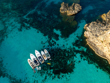 Aerial view of boats floating on the crystal clear turquoise waters alongside rocky outcrops at the Blue Lagoon Comino Malta. Aerial view of boats floating on the crystal clear turquoise waters alongside rocky outcrops at the Blue Lagoon Comino Malta.