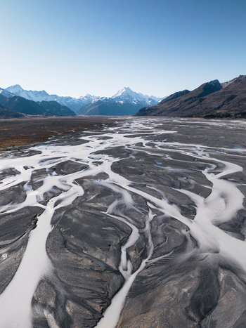 Aerial view of braided rivers carve through the landscape towards snow capped mountains under a clear sky Lake Tekapo Canterbury Region New Zealand. Aerial view of braided rivers carve through the landscape towards snow capped mountains under a clear sky Lake Tekapo Canterbury Region New Zealand.