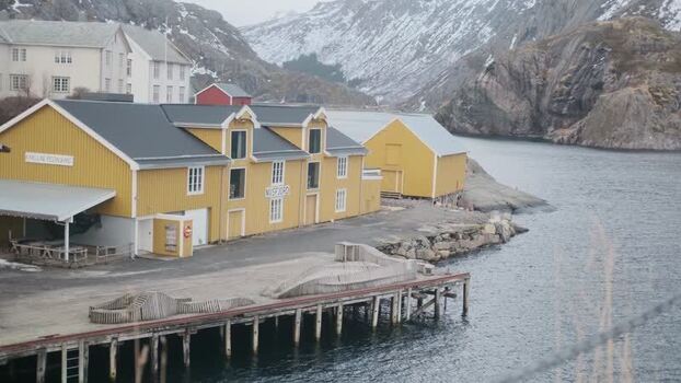 View of Nusfjord buildings and snowy mountains Norway.