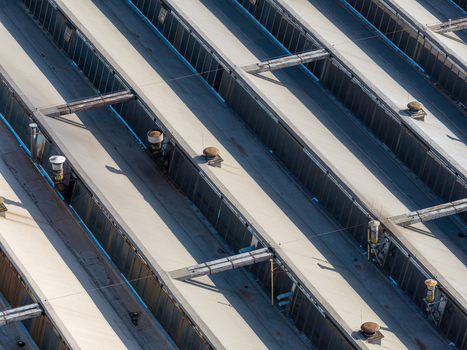 Aerial view of old factory roof with metal panels ventilation units and structural beams under bright daylight in Plock Wojewodztwo mazowieckie Poland. Aerial view of old factory roof with metal panels ventilation units and structural beams under bright daylight in Plock Wojewodztwo mazowieckie Poland.