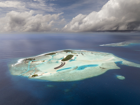 Aerial view of a tropical island resort with overwater bungalows surrounded by a turquoise lagoon and deep blue ocean in the Maldives. Aerial view of a tropical island resort with overwater bungalows surrounded by a turquoise lagoon and deep blue ocean in the Maldives.