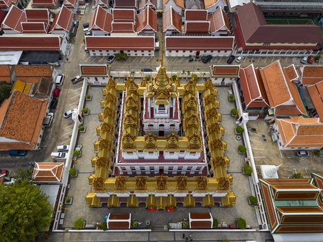 Bangkok Thailand 26 April 2026 Aerial view of the golden spires of Loha Prasat at Wat Ratchanatdaram temple complex surrounded by traditional red roofed buildings.