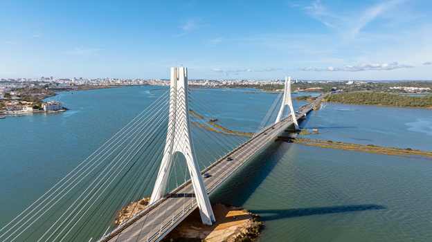 Aerial view of the Arade Bridge spanning the Arade River with urban surroundings under a clear blue sky in Portimao Faro District Portugal. Aerial view of the Arade Bridge spanning the Arade River with urban surroundings under a clear blue sky in Portimao Faro District Portugal.