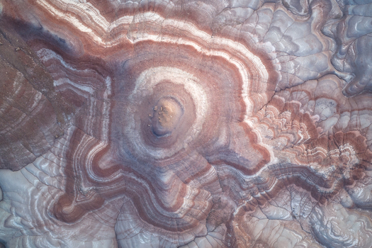 Aerial view of the mesmerizing concentric rings of earth tones swirling around a central peak creating a natural masterpiece of geological artistry Hanksville Utah United States. Aerial view of the mesmerizing concentric rings of earth tones swirling around a central peak creating a natural masterpiece of geological artistry Hanksville Utah United States.