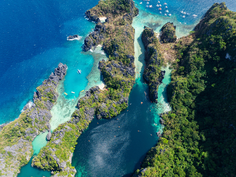 Aerial view of the Big Lagoon and Small Lagoon area with limestone cliffs turquoise waters and lush tropical vegetation in El Nido Philippines.