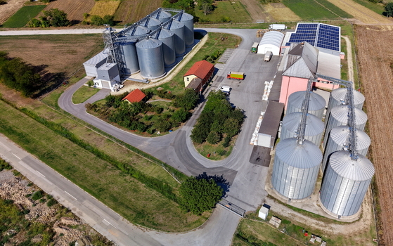 Aerial view of storage silo Bavaniste with large metal grain containers surrounding agricultural fields and solar panels on the roof in Bavaniste Vojvodina Serbia.