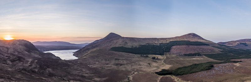 Aerial view of Altan Lough at sunset featuring rolling mountains coniferous forests and rugged terrain in County Donegal Ireland.