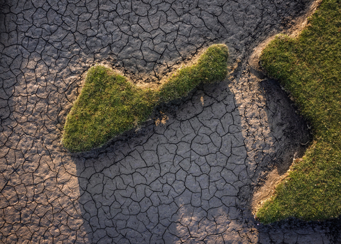 Aerial view of the parched cracked earth and patches of green grass at Portmarnock Beach under warm sunlight County Dublin Ireland. Aerial view of the parched cracked earth and patches of green grass at Portmarnock Beach under warm sunlight County Dublin Ireland.