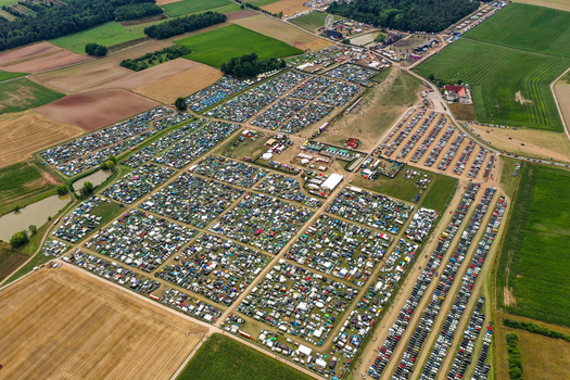 Herzogenaurach Germany 24 July 2025 Aerial view of the Open Beatz Festival campsite with thousands of tents and parked cars surrounded by agricultural fields and forests.