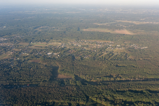Aerial view of vast green forests and scattered buildings with patches of open fields under a hazy sky Otwock Masovian Voivodeship Poland. Aerial view of vast green forests and scattered buildings with patches of open fields under a hazy sky Otwock Masovian Voivodeship Poland.