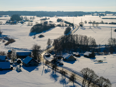 Aerial view of a snow covered rural landscape with a winding road traditional houses and a small aircraft parked in the snow Lithuania. Aerial view of a snow covered rural landscape with a winding road traditional houses and a small aircraft parked in the snow Lithuania.