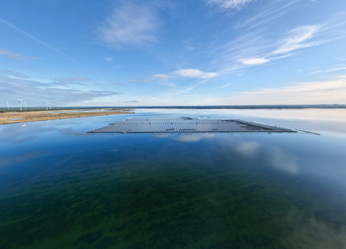 Aerial view of the floating solar farm on Cottbuser Ostsee showing repair works after storm damage with wind turbines in the background under a clear sky in Cottbus Brandenburg Germany. Aerial view of the floating solar farm on Cottbuser Ostsee showing repair works after storm damage with wind turbines in the background under a clear sky in Cottbus Brandenburg Germany.