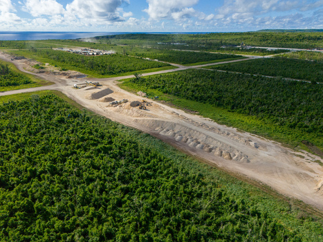 Aerial view of the restoration of North Field Base showing industrial equipment large sand piles and dirt roads in Northern Tinian Tinian Northern Mariana Islands.