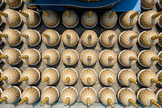 Aerial view of golden brown and cream decorative conical objects arranged in perfect rows on a light gray surface Tangail Dhaka Division Bangladesh. Aerial view of golden brown and cream decorative conical objects arranged in perfect rows on a light gray surface Tangail Dhaka Division Bangladesh.