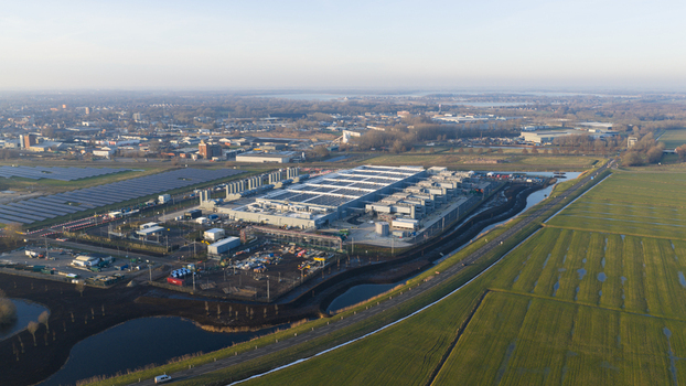 Aerial view of a large industrial facility and solar farm surrounded by green fields and canals in Winschoten Groningen Netherlands.