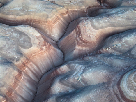 Aerial view of swirling patterns of layered rock formations create a mesmerizing landscape of earth tones and textures Hanksville Utah United States. Aerial view of swirling patterns of layered rock formations create a mesmerizing landscape of earth tones and textures Hanksville Utah United States.