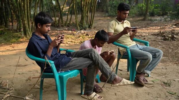 View of three young men using smartphones in Bogura Bangladesh. View of three young men using smartphones in Bogura Bangladesh.