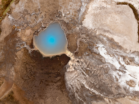 Aerial view of a vibrant blue geothermal pool surrounded by barren volcanic terrain and mineral deposits Reykjanesbaer Iceland. Aerial view of a vibrant blue geothermal pool surrounded by barren volcanic terrain and mineral deposits Reykjanesbaer Iceland.