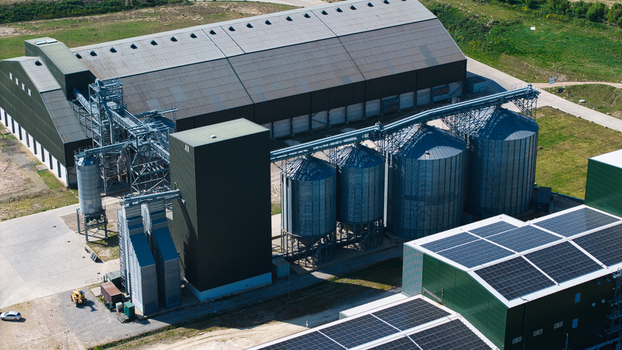 Aerial view of the Oat Milling Factory featuring large silver grain silos industrial warehouses and rooftop solar panels under bright sunlight in Kettering England United Kingdom. Aerial view of the Oat Milling Factory featuring large silver grain silos industrial warehouses and rooftop solar panels under bright sunlight in Kettering England United Kingdom.