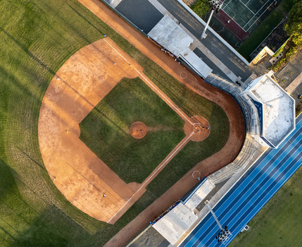 Aerial view of a baseball field with a dirt infield and green grass outfield adjacent to a running track in Santo Domingo Distrito Nacional Dominican Republic.