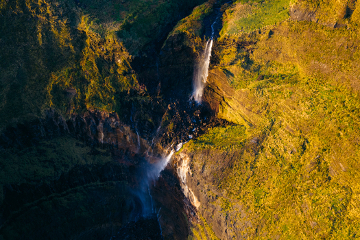 Aerial view of Poco da Ribeira do Ferreiro waterfall cascading down steep green cliffs during golden hour in Fajazinha Azores Portugal. Aerial view of Poco da Ribeira do Ferreiro waterfall cascading down steep green cliffs during golden hour in Fajazinha Azores Portugal.