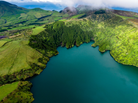 Aerial view of a stunning lake embraced by verdant hills and dense forests where the water reflects the sky s tranquil blues Flores Azores Portugal.