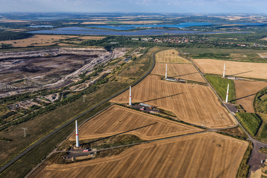 Aerial view of the Schleenhain lignite open cast mine adjacent to agricultural fields with wind turbines in Zwenkau Saxony Germany.