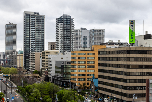 View of the modern cityscape of Sapporo with high rise buildings urban streets and lush green trees in Sapporo Hokkaido Japan. View of the modern cityscape of Sapporo with high rise buildings urban streets and lush green trees in Sapporo Hokkaido Japan.