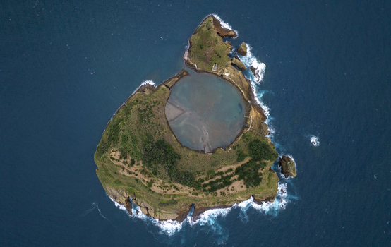 Aerial view of the volcanic islet Ilheu de Vila Franca do Campo featuring a circular crater lagoon and lush green vegetation surrounded by the Atlantic Ocean in Sao Pedro Acores Portugal. Aerial view of the volcanic islet Ilheu de Vila Franca do Campo featuring a circular crater lagoon and lush green vegetation surrounded by the Atlantic Ocean in Sao Pedro Acores Portugal.