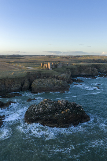 Aerial view of the ruined Slains Castle also known as Dracula s Castle perched on rugged cliffs overlooking the North Sea at Cruden Bay Scotland United Kingdom. Aerial view of the ruined Slains Castle also known as Dracula s Castle perched on rugged cliffs overlooking the North Sea at Cruden Bay Scotland United Kingdom.