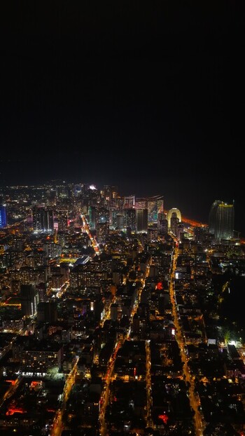 Batumi Georgia 17 September 2026 Aerial view of the illuminated cityscape of Batumi at night featuring glowing skyscrapers vibrant street lights and the dark coastline.