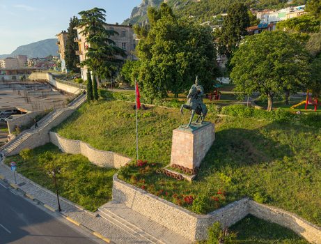 Aerial view of the Skanderbeg Monument equestrian statue on a stone pedestal surrounded by green grass and lush trees in the historic town of Kruje Durres County Albania.