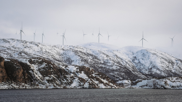 View of wind turbines standing tall on snow dusted hills under a soft overcast sky creating a serene yet powerful landscape Brensholmen Troms Norway. View of wind turbines standing tall on snow dusted hills under a soft overcast sky creating a serene yet powerful landscape Brensholmen Troms Norway.