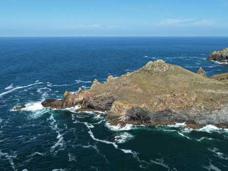 Aerial view of The Rumps a dramatic rocky headland with rugged cliffs and crashing waves surrounded by the deep blue Atlantic Ocean in Wadebridge England United Kingdom. Aerial view of The Rumps a dramatic rocky headland with rugged cliffs and crashing waves surrounded by the deep blue Atlantic Ocean in Wadebridge England United Kingdom.