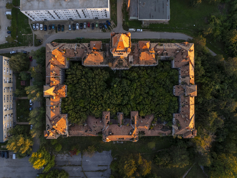 Aerial view of the abandoned Hajmasker Barracks featuring a large rectangular building with orange tiled roofs and a dense forest growing within its central courtyard. Hajmasker Hungary. Aerial view of the abandoned Hajmasker Barracks featuring a large rectangular building with orange tiled roofs and a dense forest growing within its central courtyard. Hajmasker Hungary.