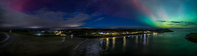 Aerial view of the Aurora Borealis illuminating the night sky above the coastal village of Portnoo County Donegal Ireland.