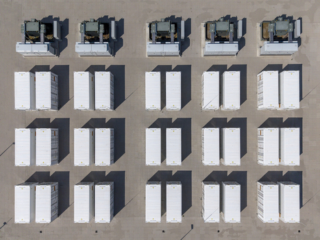 Aerial view of Battery Energy Storage System at Wind Park featuring rows of white containers and electrical equipment casting long shadows on the ground in Dronten Flevoland Netherlands. Aerial view of Battery Energy Storage System at Wind Park featuring rows of white containers and electrical equipment casting long shadows on the ground in Dronten Flevoland Netherlands.