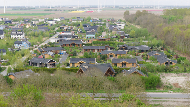 Aerial view of Ecodorp Bolderburen featuring sustainable wooden houses with solar panels wind turbines and tulip fields on the horizon in Almere Flevoland Netherlands. Aerial view of Ecodorp Bolderburen featuring sustainable wooden houses with solar panels wind turbines and tulip fields on the horizon in Almere Flevoland Netherlands.