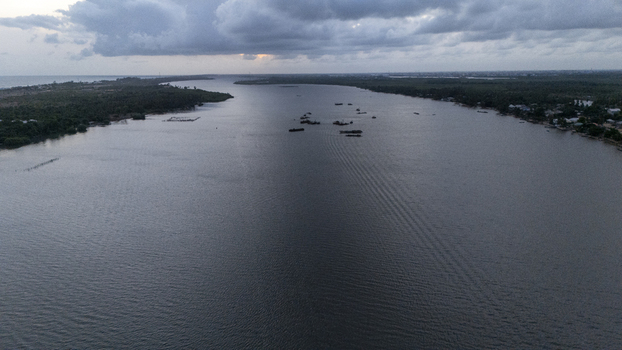 Aerial view of the wide Badagry Creek with small boats scattered on the water under a dramatic cloudy sky at dusk Badagry Lagos Nigeria. Aerial view of the wide Badagry Creek with small boats scattered on the water under a dramatic cloudy sky at dusk Badagry Lagos Nigeria.